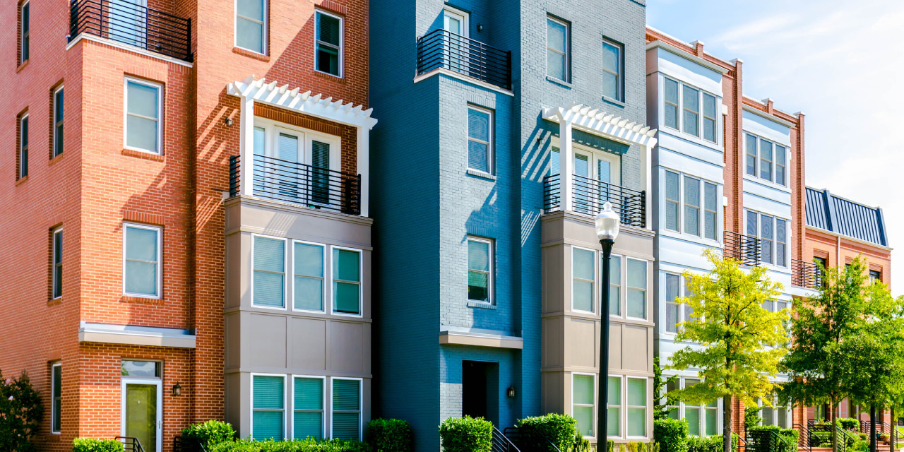 exterior of colorful multifamily apartment building against blue sky