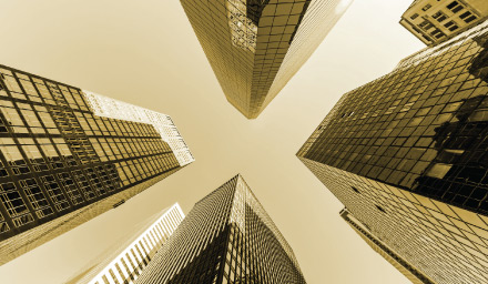 Looking up at tall glass office buildings with gold overlay