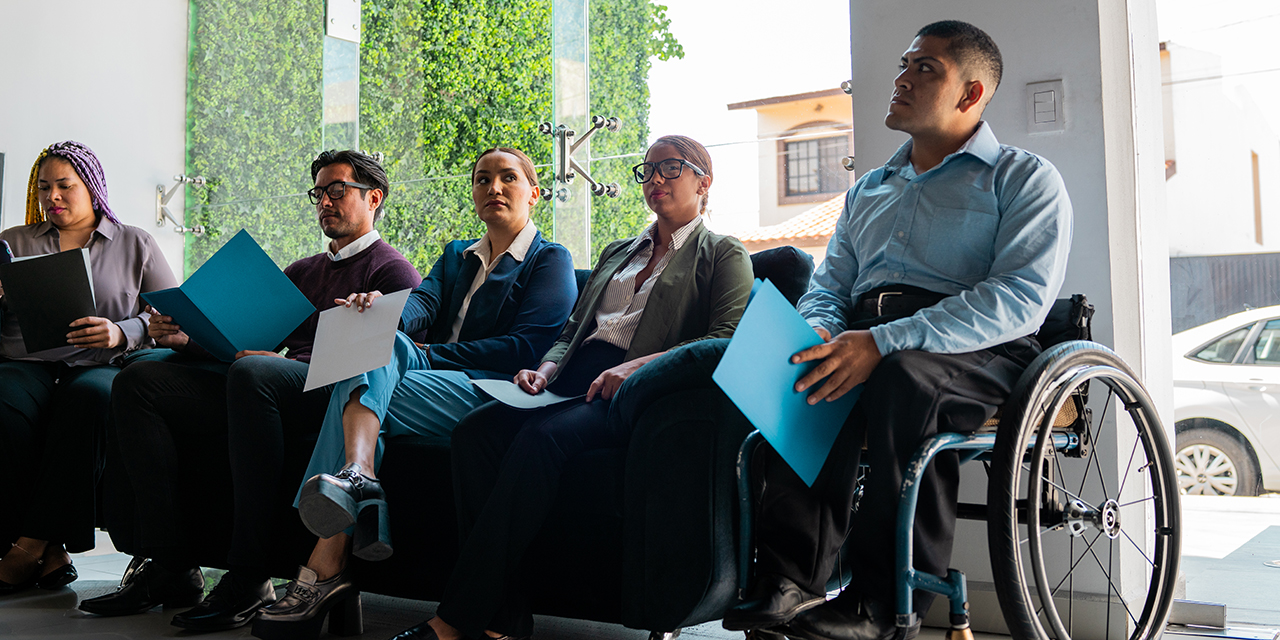 group of people, including a person using a wheelchair, waiting in an office group of people, including a person using a wheelchair, waiting in an office