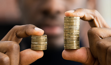 closeup of person holding a stack of coins in each hand, one stack larger than the other