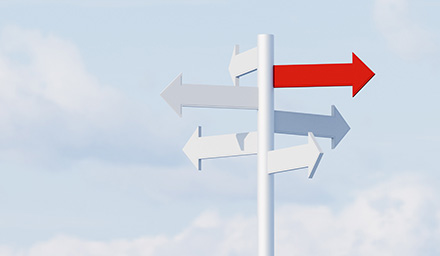 Photo: Conceptual image of a directional sign with arrow in all directions and one red one standing out from the rest